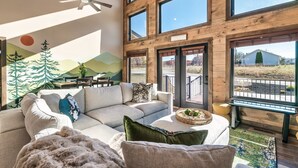 A spacious living room with a large sofa, a coffee table, and a view of the outside.