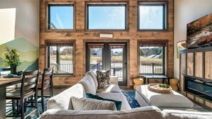 A spacious living area with a large wooden wall, multiple windows, and a view of the outdoors.