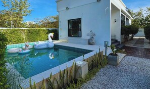 Ein Poolbereich im modernen Stil mit einem weißen Gebäude, einem Schwimmschwan und Luftmatratzen.