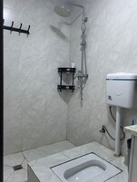Ein Badezimmer mit Dusche, Toilette und Warmwasserbereiter.