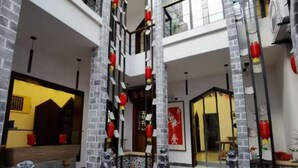 A multi-level interior with a central staircase, stone pillars, and red lanterns.