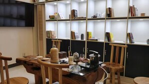 A modern interior with a wooden table, chairs, a bookshelf, and a flat-screen TV.