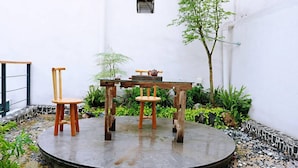A round table with chairs in a courtyard with white walls and greenery.