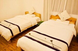 Dos camas individuales con estructuras de madera, ropa blanca y detalles oscuros.