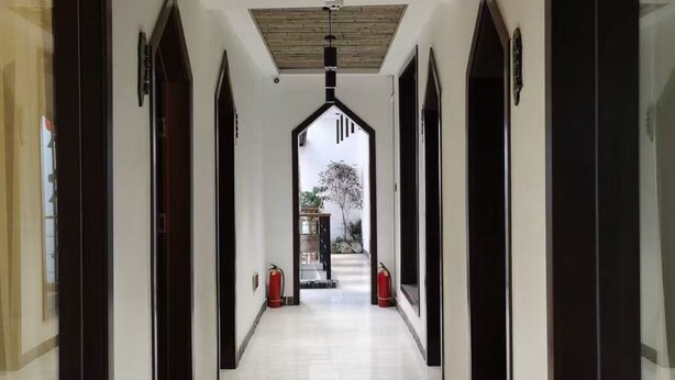 A hallway with a modern design, featuring a straight path with arched doorways on both sides, leading to a staircase at the end.
