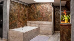 Une salle de bain moderne avec une baignoire sur pieds, des murs en marbre et une lucarne.