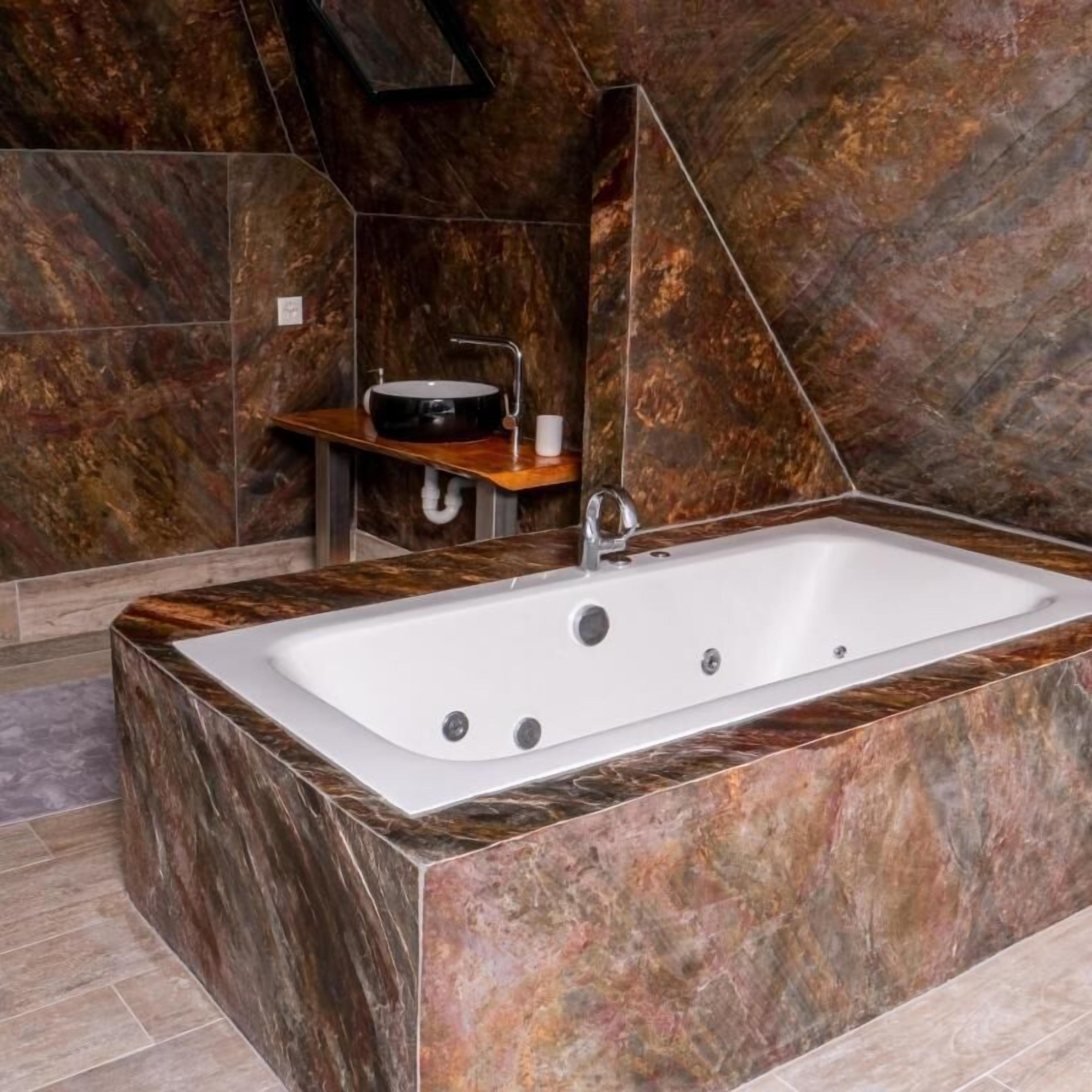 Ein modernes Badezimmer mit einer rechteckigen Badewanne, einem kleinen Waschbecken mit schwarzer Schüssel und einer Holzablage.