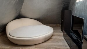 Une salle de bain moderne avec une baignoire aux formes originales et incurvées, un plancher en bois et un meuble-lavabo aux tons foncés.