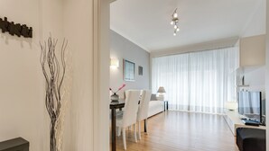 Un salon moderne comprenant un coin repas, un plancher en bois, un téléviseur et un vase décoratif.