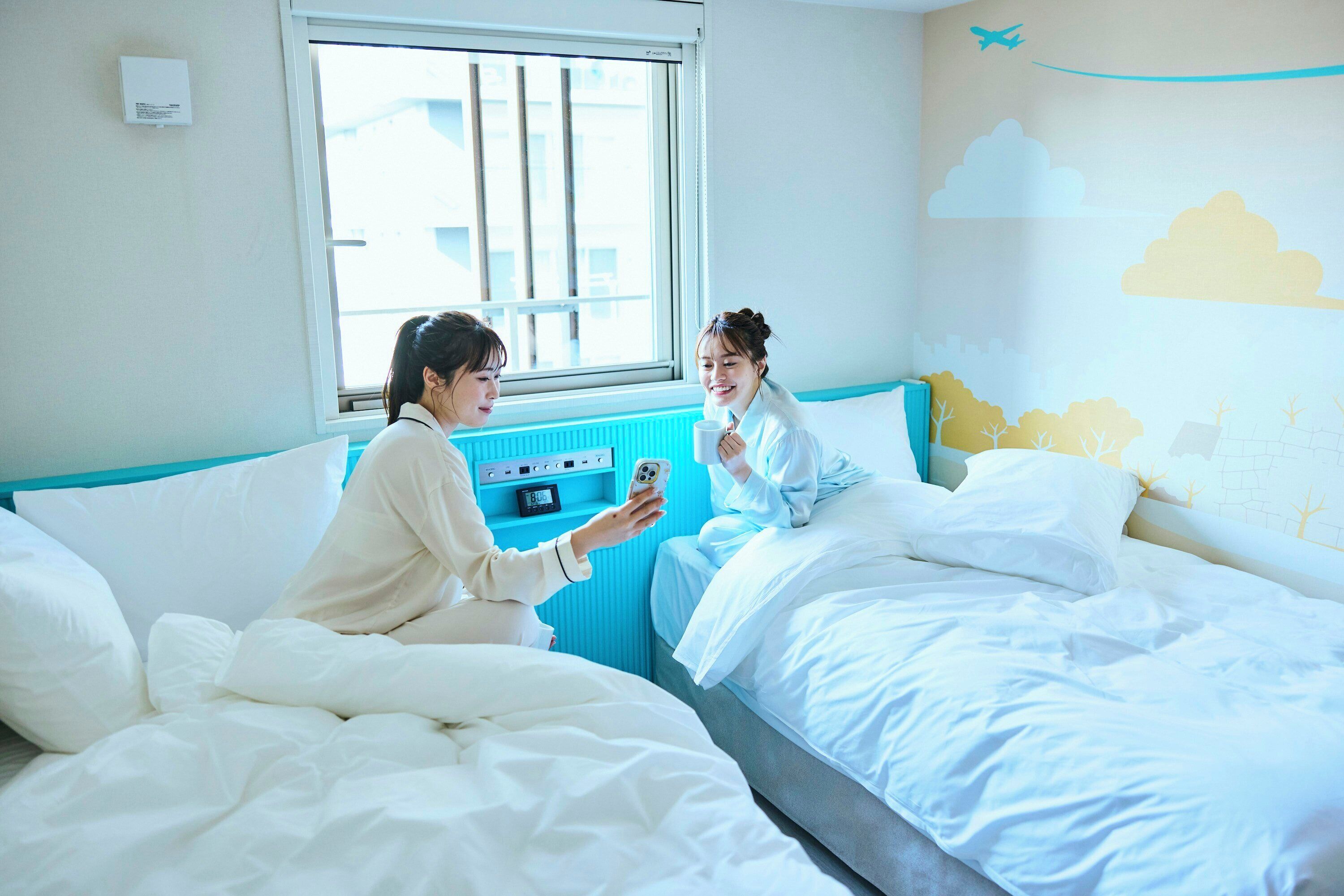 A bedroom with a bed, a bedside table, a window, and a wall mural.