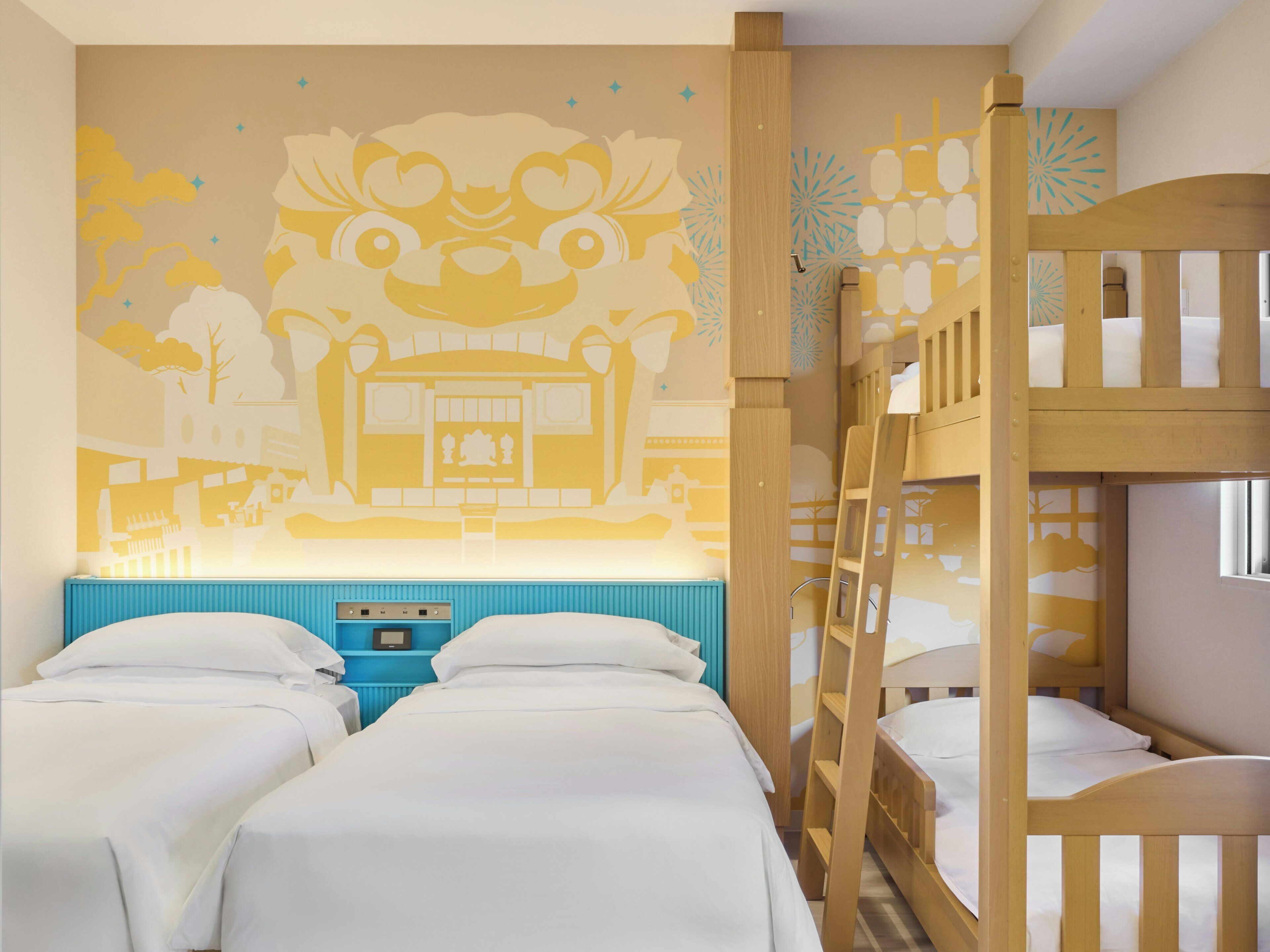 A room with two beds, a bunk bed, a wall mural, and a blue bedside table.
