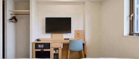 Habitación de hotel con dos camas, un escritorio con silla, televisión, armario y ventana.