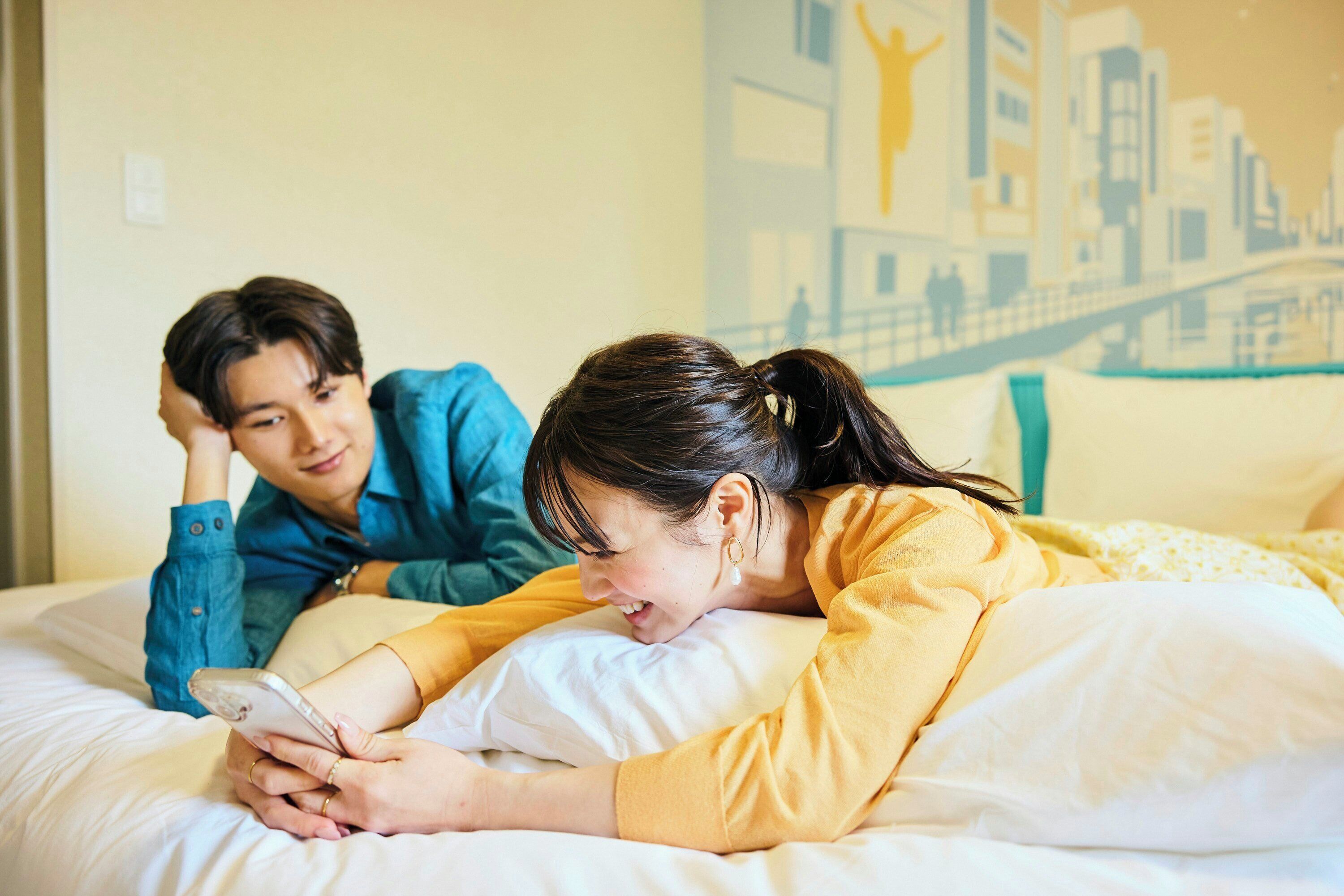 A bed with white bedding and a cityscape mural on the wall.