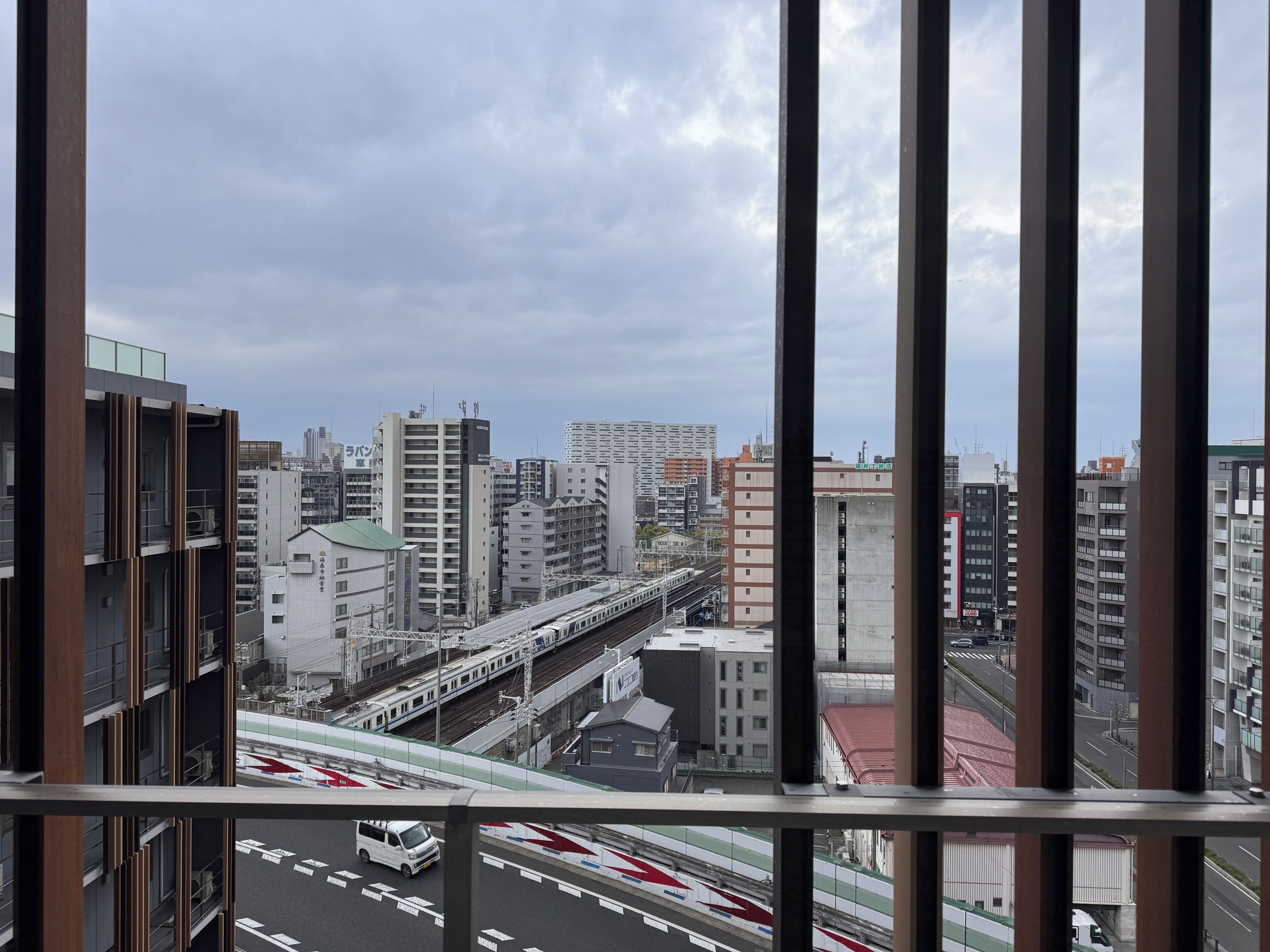 Une vue urbaine avec de hauts immeubles, une voie ferrée et une route où circulent des véhicules.