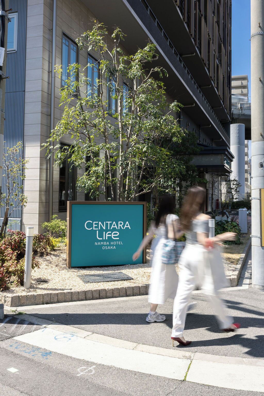 Une enseigne indiquant l’hôtel Centara Life Namba à Osaka, avec un bâtiment moderne en arrière-plan.