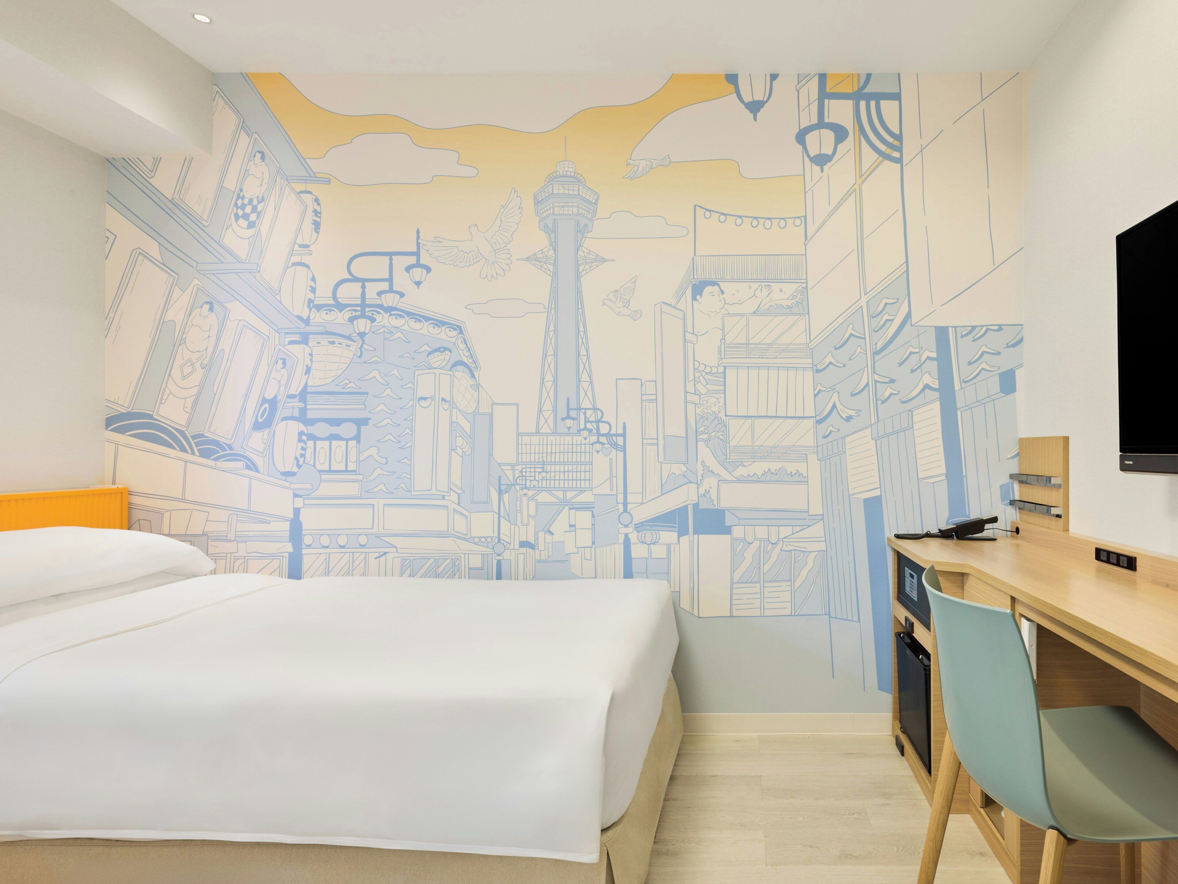 Una habitación de hotel con cama, escritorio, silla, televisor y un mural en la pared.