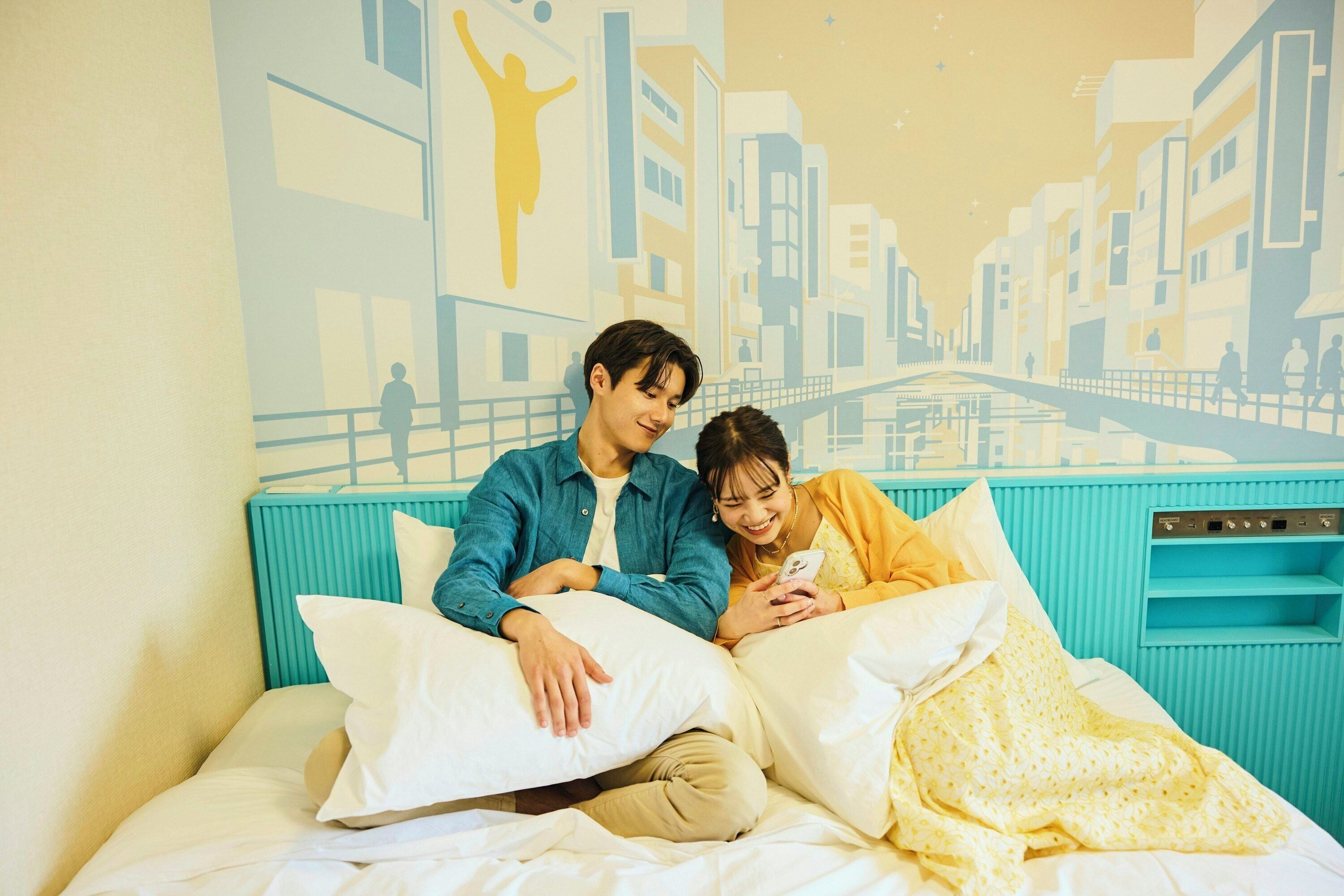 A bed with a cityscape mural, a teal headboard, and a white pillow.