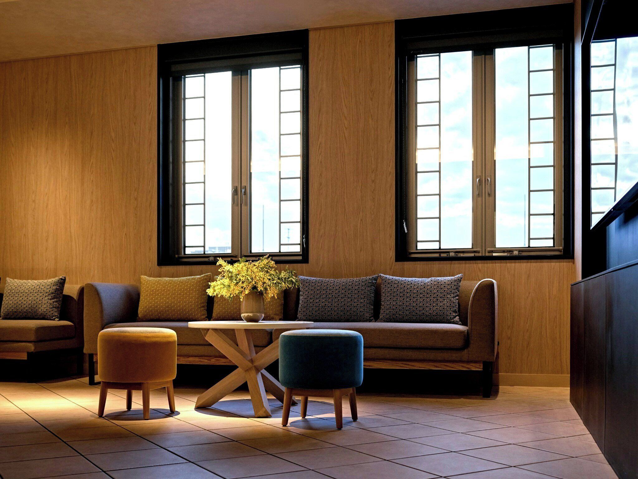 A modern living room with a sofa, ottomans, and a coffee table.