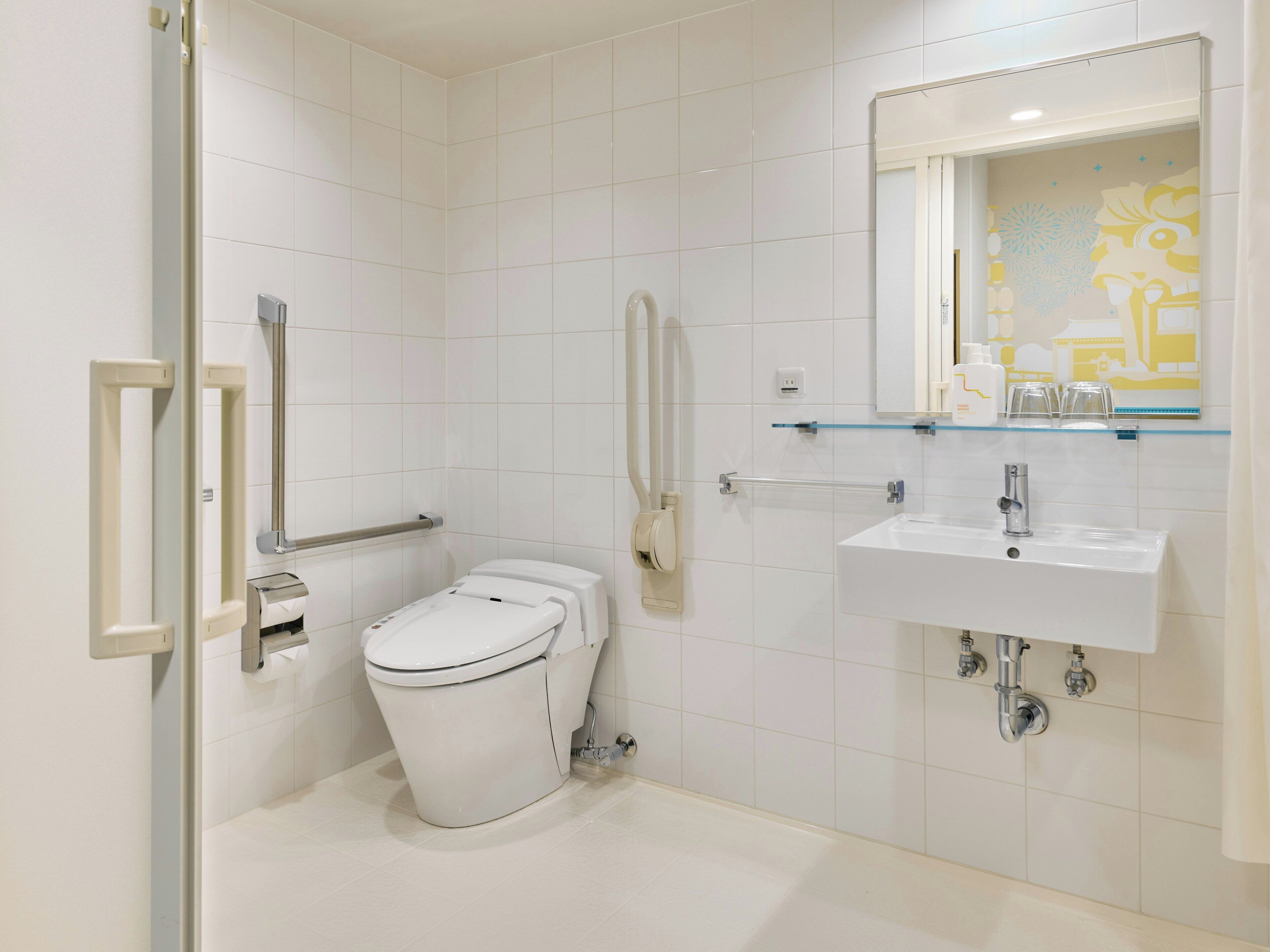 Ein modernes Badezimmer mit Toilette, Bidet, Handtrockner und Ablage über dem Waschbecken.