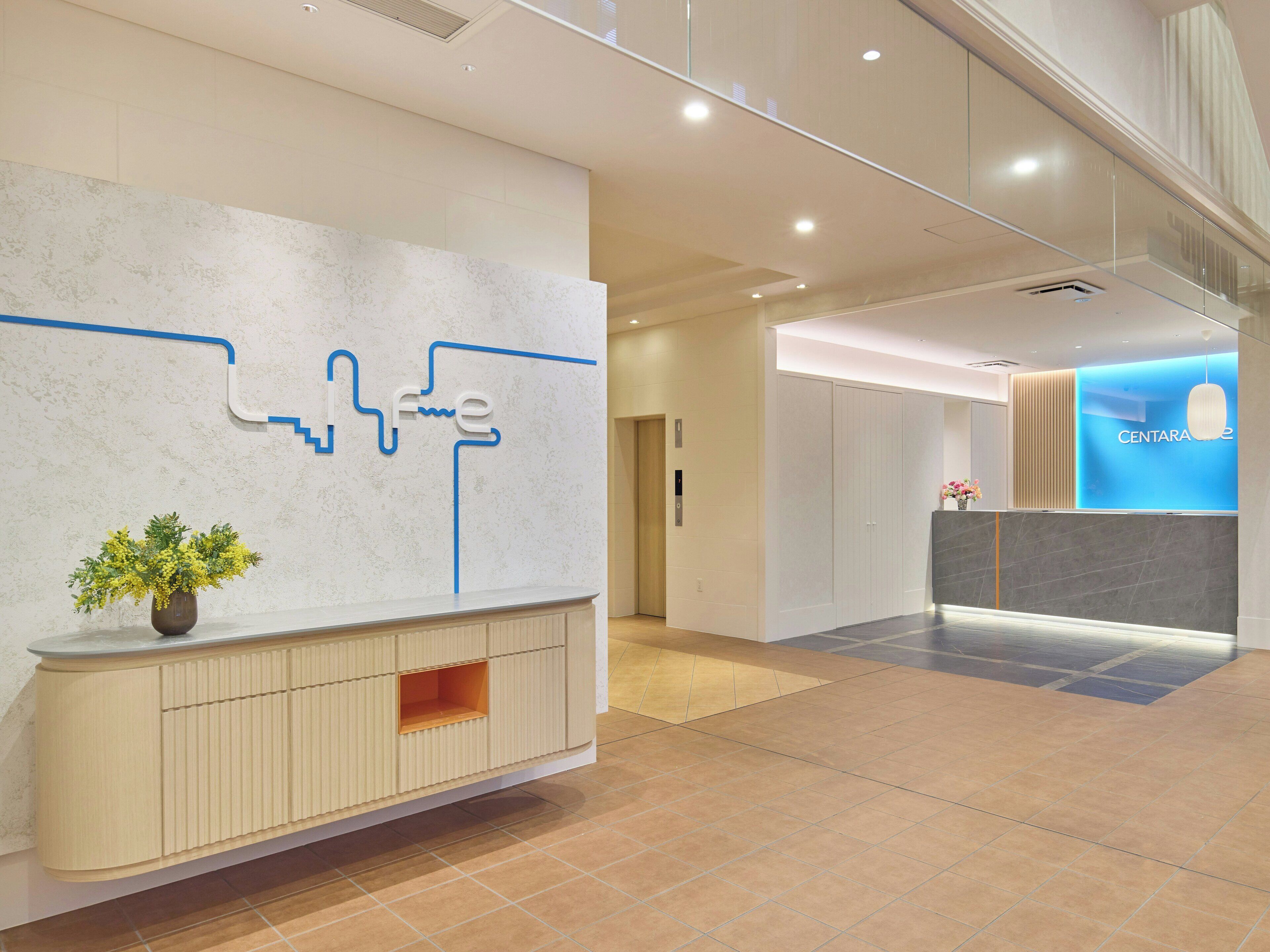 A modern reception area with a marble wall, a reception desk, and a blue illuminated sign.