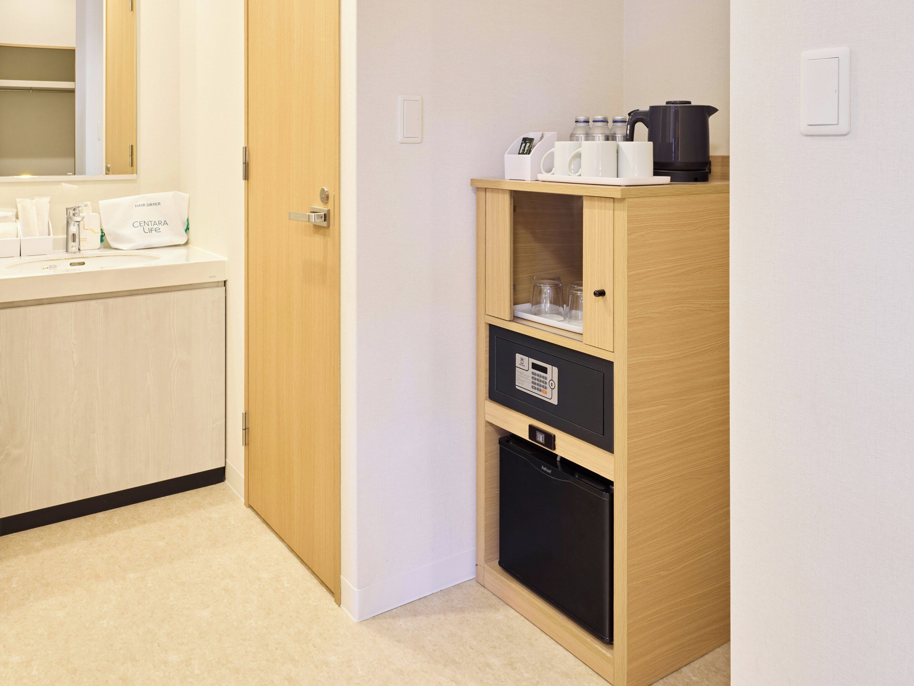 Un baño de hotel con un mueble de madera, un secador de pelo y una cafetera.