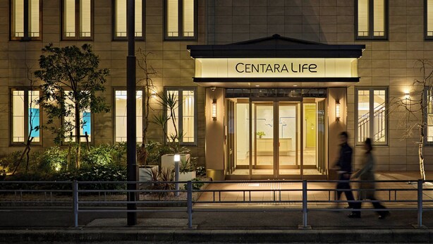 Ein Gebäude mit der Aufschrift 'CENTARA LIFE' am Eingang, mit modernem Design, großen Fenstern und einer gut beleuchteten Fassade.