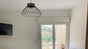 Un salon moderne avec un canapé gris, un bureau en bois et un luminaire suspendu au plafond.