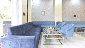 A modern interior with a blue sofa, a marble coffee table, and matching chairs. - Ricch Hotels (Jaipur)