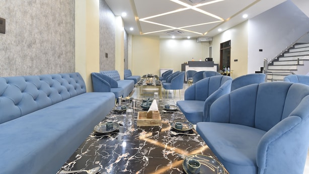 A modern hotel lobby with a marble coffee table, blue sofas, and a staircase. - Ricch Hotels (Jaipur)