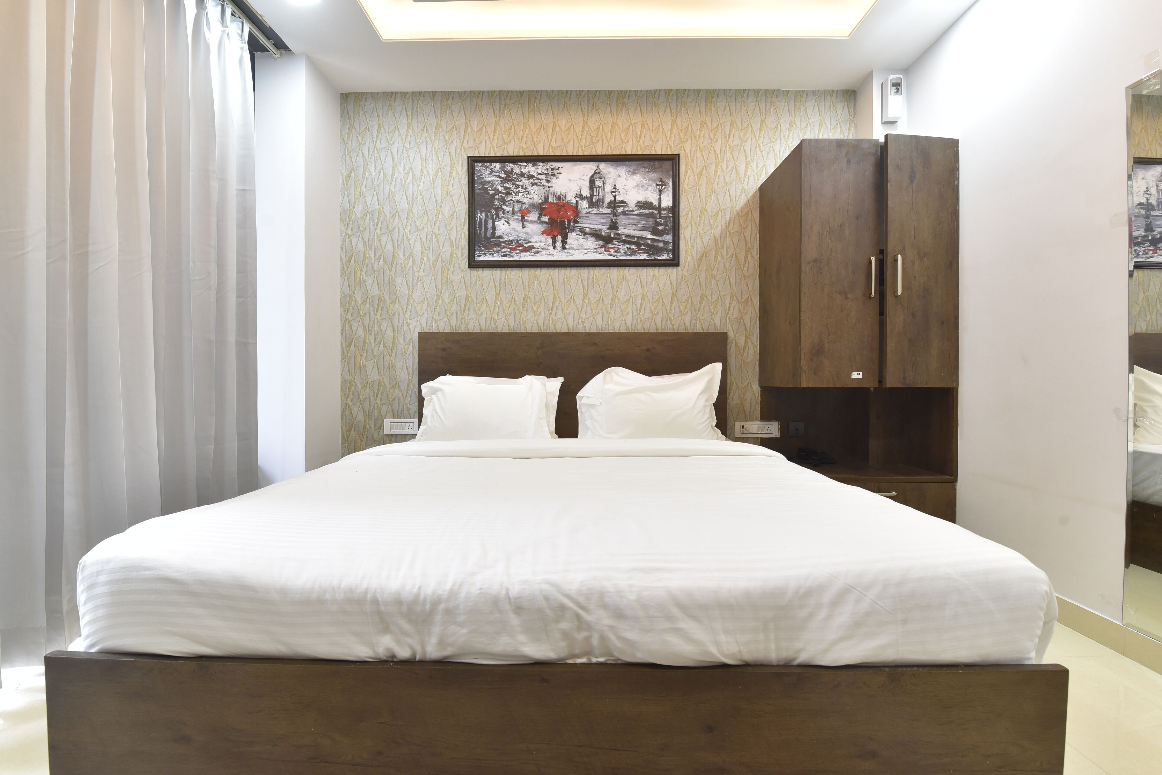A neatly made bed with white linens in a room with a wooden headboard.