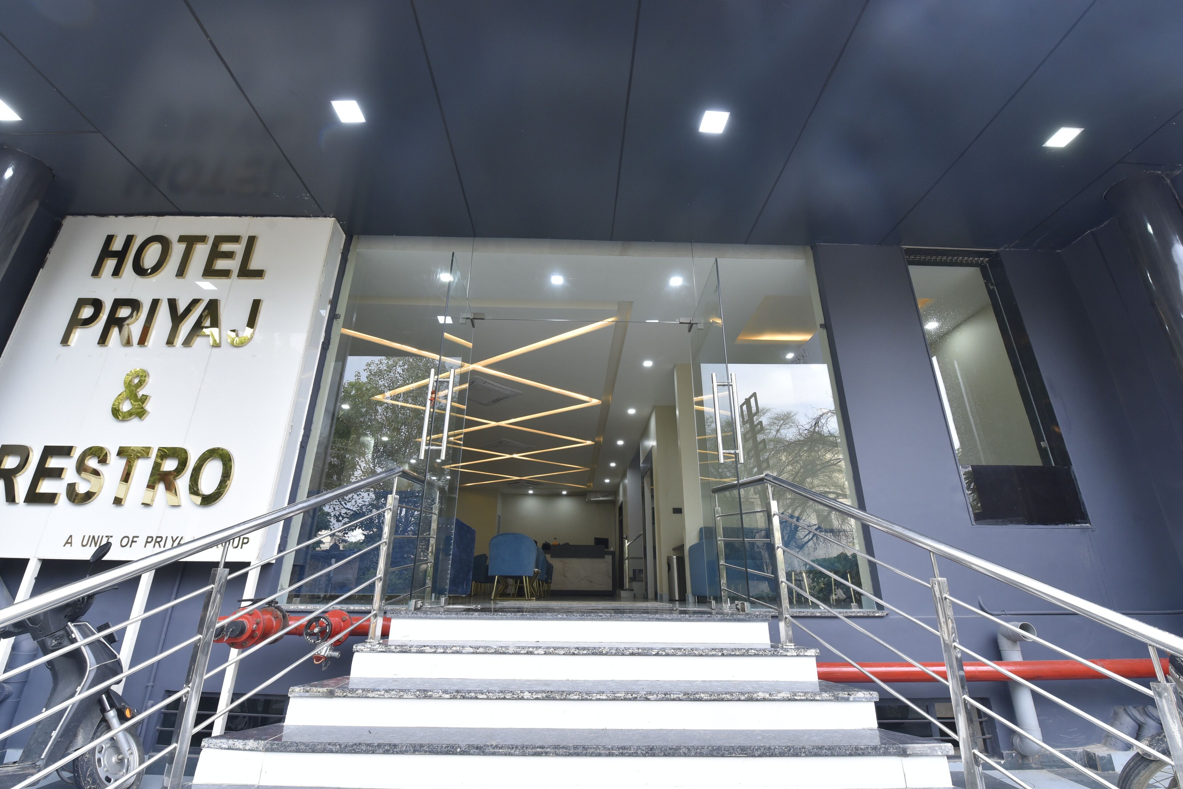 L’entrée d’un hôtel, avec une enseigne indiquant « HÔTEL PRIYA & RESTAURANT ».