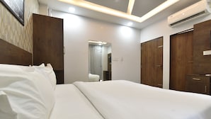 A hotel room with a large bed, wooden wardrobe, and an air conditioning unit. - Ricch Hotels (Jaipur)