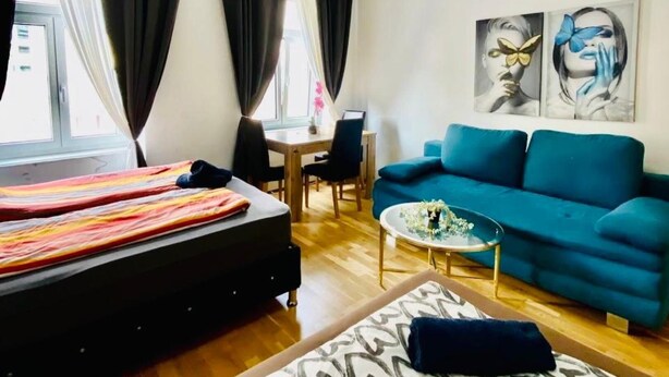 Ein modernes Zimmer mit einem Bett, einem blauen Sofa, einem kleinen Tisch und einem Bild an der Wand.