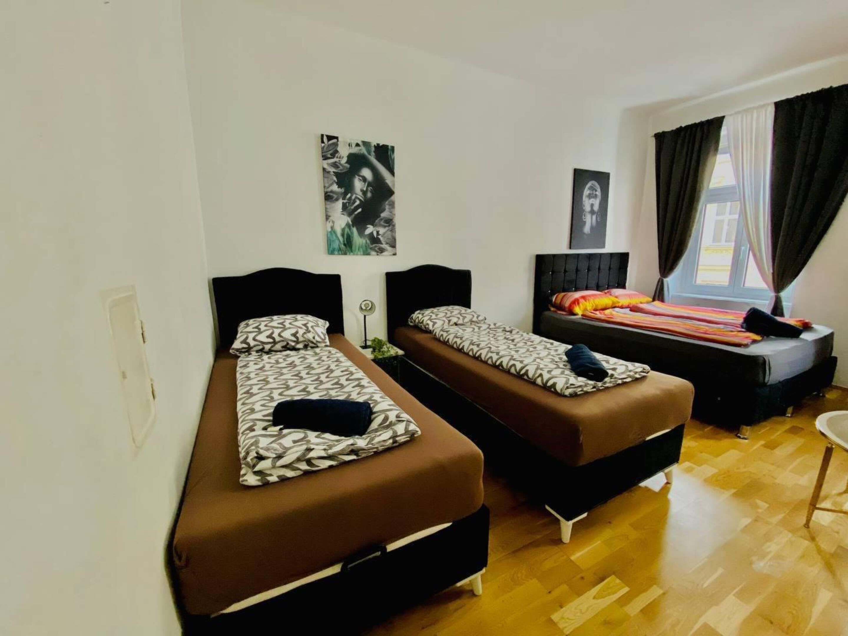 A room with two single beds, a small table, and a window with curtains.