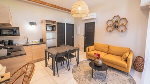 Eine moderne Wohnung mit Küche, Essbereich und Wohnzimmer. Sie verfügt über ein Sofa, einen Esstisch, Stühle, einen Couchtisch und ein dekoratives Wandregal.