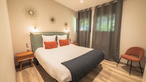 Ein ordentlich eingerichtetes Schlafzimmer mit einem großen Bett, einem Nachttisch, einem Sessel und einem Fenster mit Vorhängen.