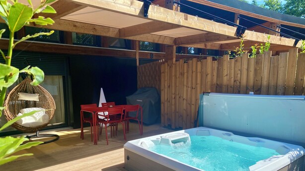 Eine Holzterrasse mit Whirlpool, roten Stühlen und einer Hängematte.