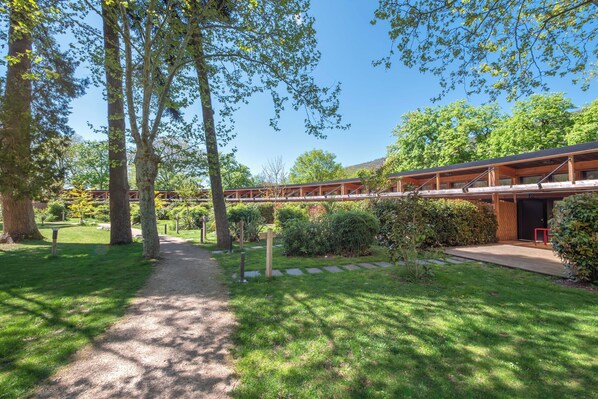 Een pad dat leidt naar een gebouw met een houten terras en een overdekte doorgang.