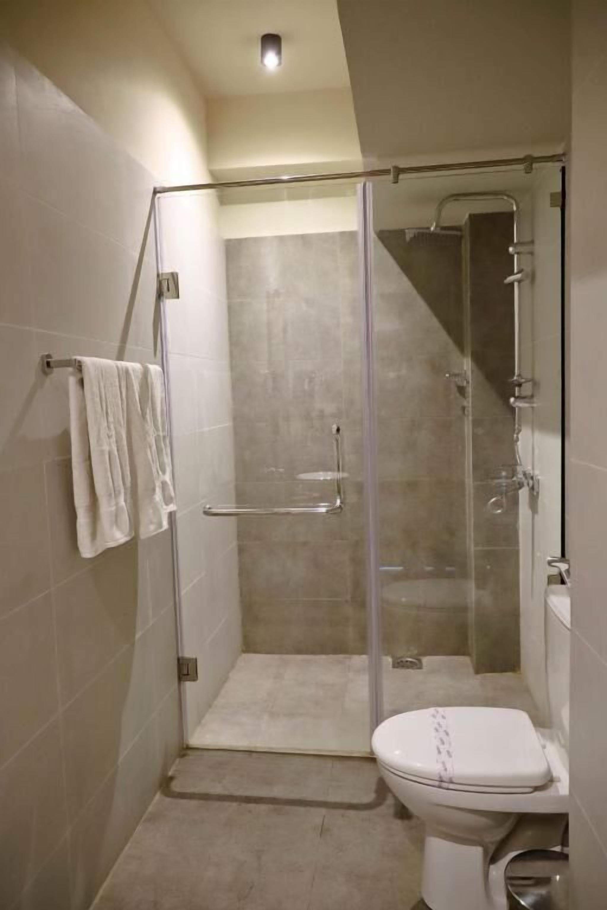A modern bathroom with a glass-enclosed shower, a white toilet, and a towel rack.