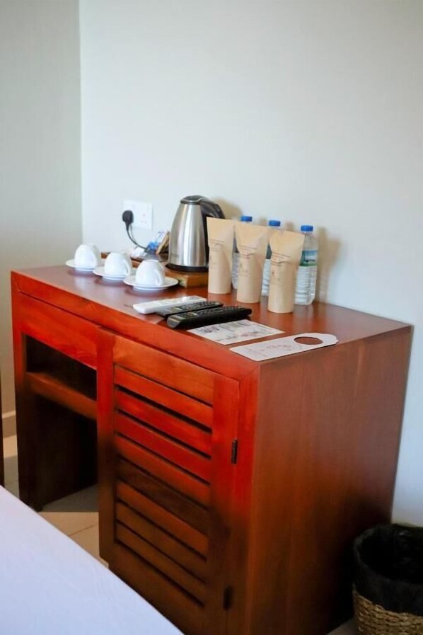 Un bureau en bois avec une bouilloire, des tasses et des bouteilles d’eau.