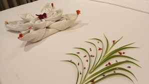 A neatly made bed with a white pillow and a towel arranged in a decorative manner. - Oak Ray La Ella Breeze (Ella)