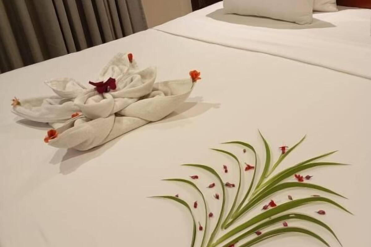 Een netjes opgemaakt bed met een wit kussen en handdoek, decoratief gerangschikt.