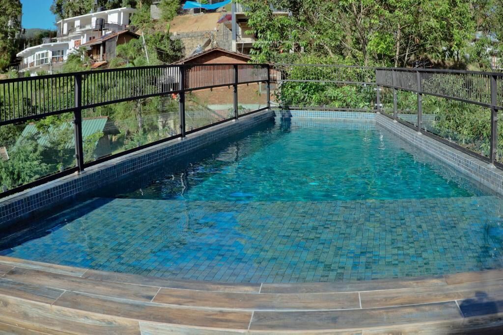 Una piscina cristallina con bordi piastrellati e un pontile in legno tutt'intorno.