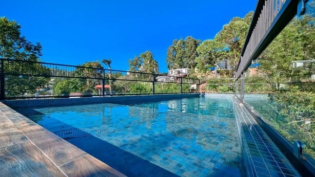 A swimming pool with clear blue water, surrounded by a wooden deck and a metal fence. - Oak Ray La Ella Breeze (Ella)