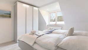 A bedroom with a bed, a wardrobe, a window, and a painting on the wall. - Vacation home "Bellaeins" in Tönning for up to 4 people (Tönning)