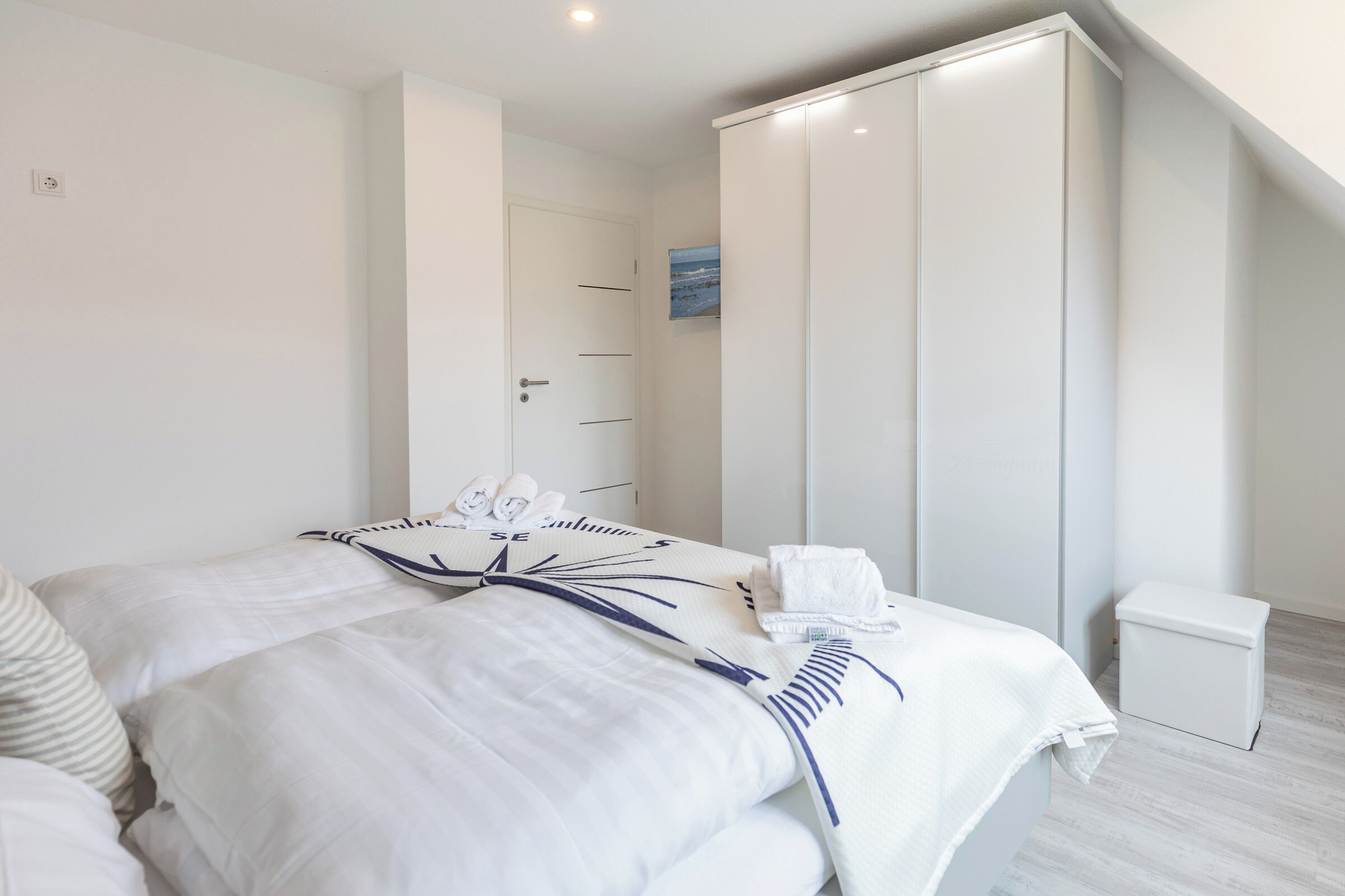 Een slaapkamer met een bed, een kledingkast en een klein wit kastje.