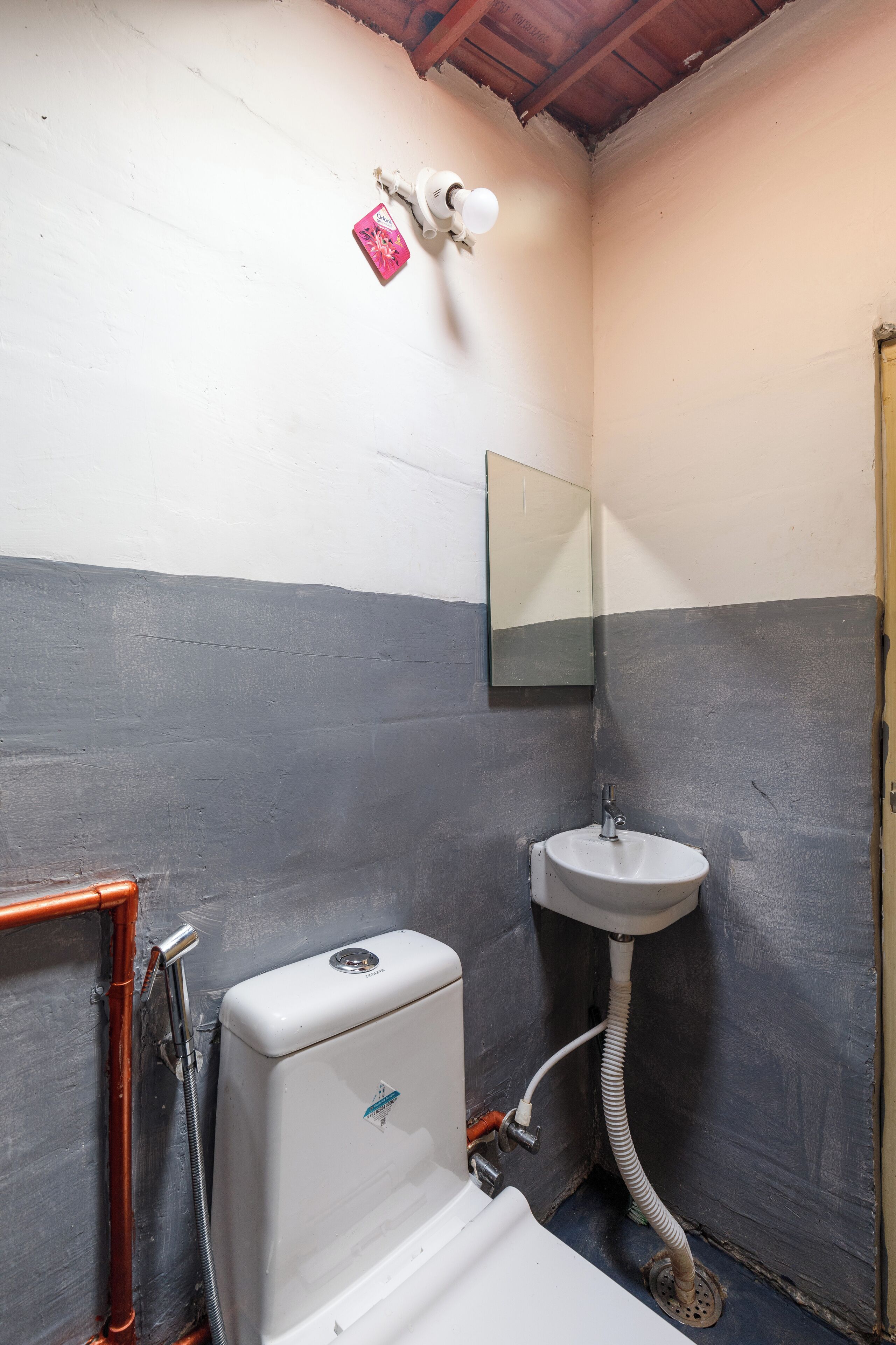 A small bathroom with a white toilet, a sink, and a mirror.