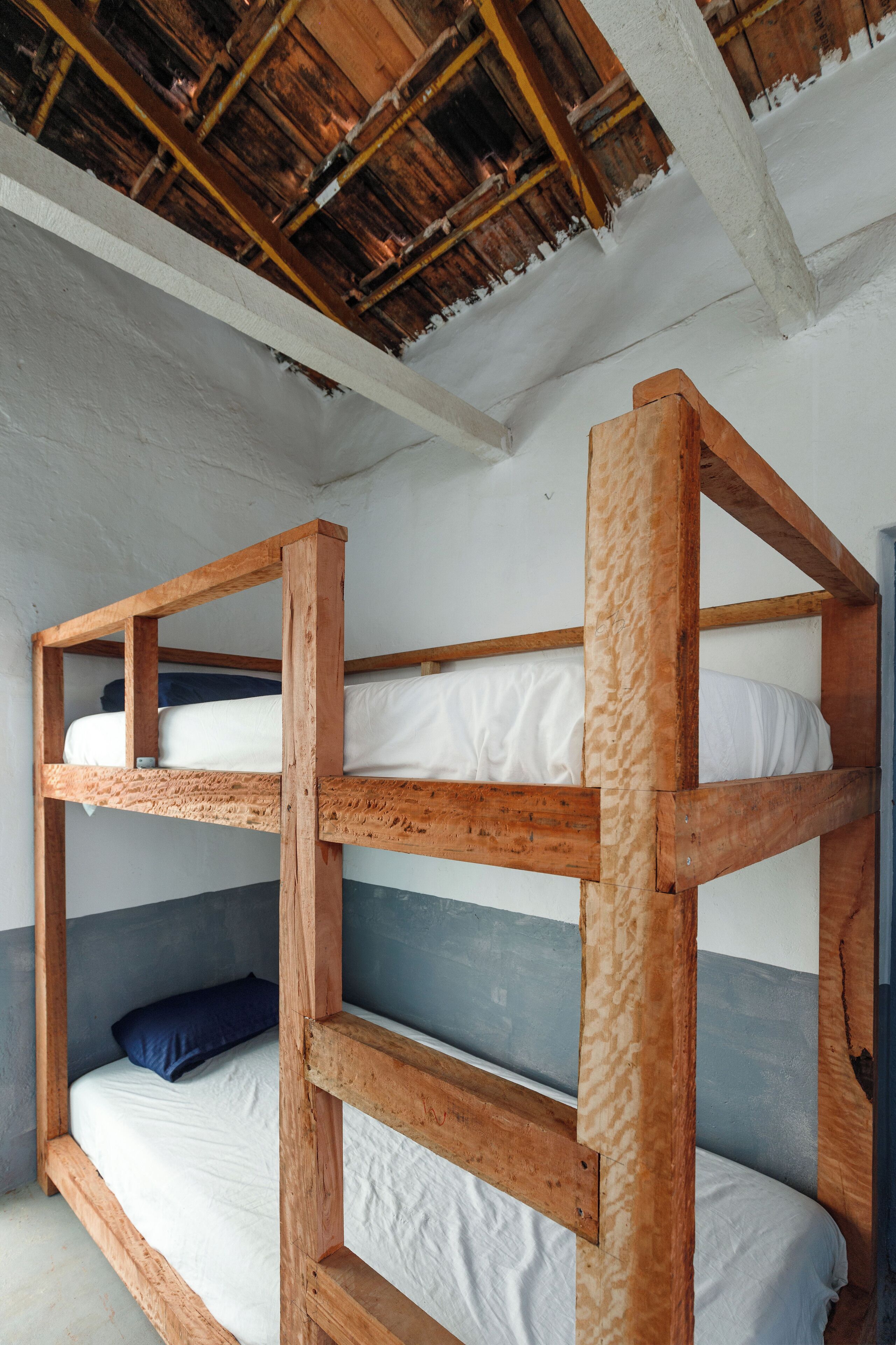 A bunk bed with white bedding and a blue pillow.