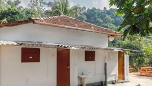 Ein eingeschossiges Gebäude mit Ziegeldach und einer kleinen Veranda, außerdem ein Waschbecken im Außenbereich.