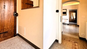 Ein Flur mit Holztür, Spiegel und einem gemusterten Teppich.